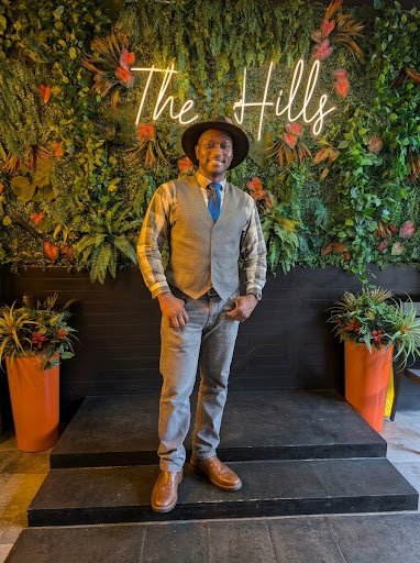 Alexander Robertson standing in front of a greenery wall
